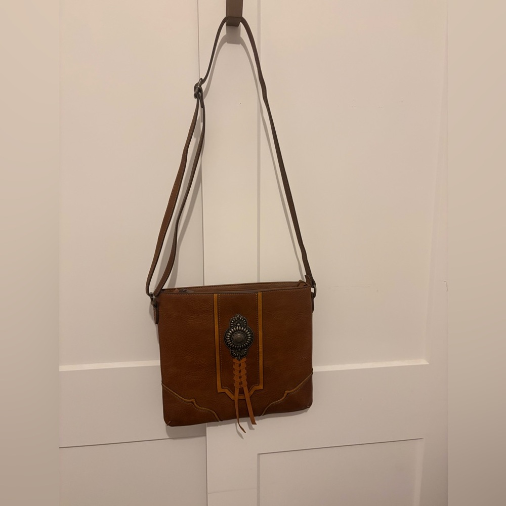 Justin Crossbody bag with silver conch and leather braid. Zipper closure.